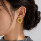 Italian silver floral statement earring with textured gold-tone petals and delicate silver accents, styled on the ear.