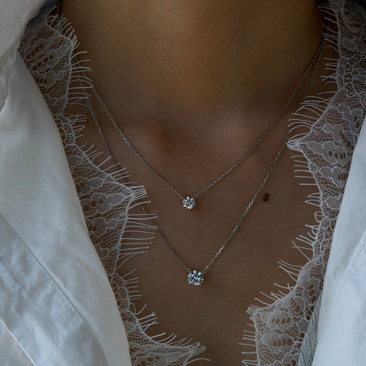 Platinum solitaire necklaces featuring 0.5-carat and 1-carat round brilliant lab-grown diamonds, layered together on delicate platinum chains.